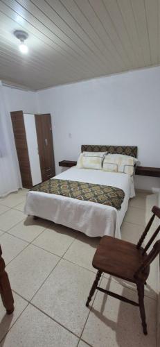 a bedroom with two beds and a wooden chair at Apartmento 3 in Santa Vitória do Palmar