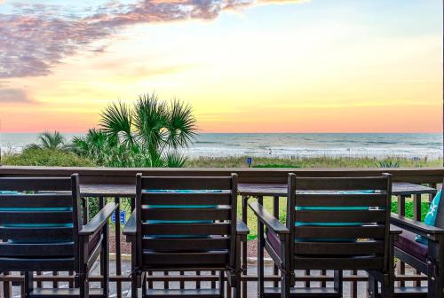 two chairs sitting on the beach at sunset at Modern Escape - Luxe Oceanfront 2BR with Epic Kitchen, Pool, Parking in Myrtle Beach