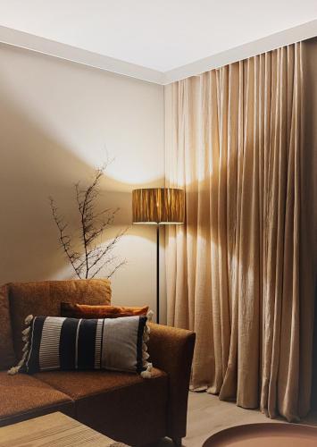 a living room with a couch and a lamp and curtains at Leśniczanka in Brenna