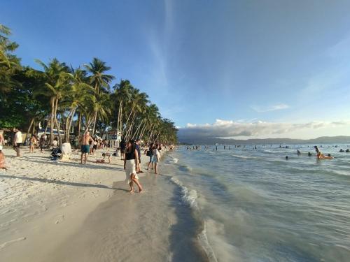 a group of people on a beach with palm trees at RenSea Haven Boracay Rm10 in Boracay