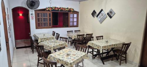 a restaurant with tables and chairs and a red door at Pousada Fonseca in Itanhaém