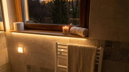 ein Badezimmer mit Fenster, mit Handtuch und Kerze in der Unterkunft Casa de sub Brazi Relaxare la munte cu Ciubar in Fîntînele