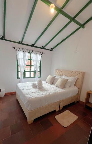 a bedroom with a bed with white sheets and a window at Alta Vibracion Casa Boutique in Villa de Leyva