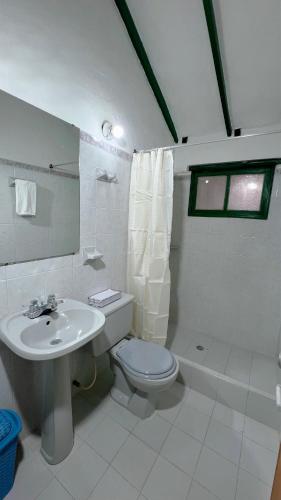 a white bathroom with a toilet and a sink at Alta Vibracion Casa Boutique in Villa de Leyva