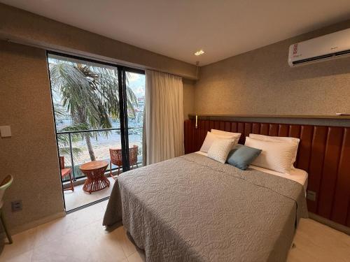ein Schlafzimmer mit einem Bett und einem großen Fenster in der Unterkunft Garden Haus Beira-Mar, Jardim Oceania-Miramar Hospedagens in Tambaú