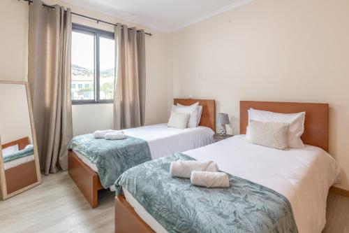 zwei Betten in einem Zimmer mit Fenster in der Unterkunft Apartamento Ruby in Machico