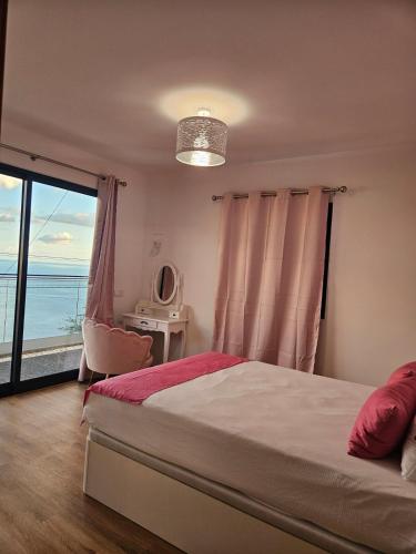 a bedroom with a bed and a view of the ocean at Villa Barros in Câmara de Lobos