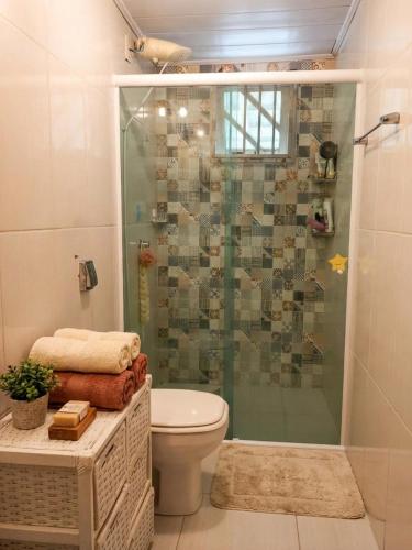 een badkamer met een glazen douche met toilet bij Casa Rústica em Garopaba in Garopaba