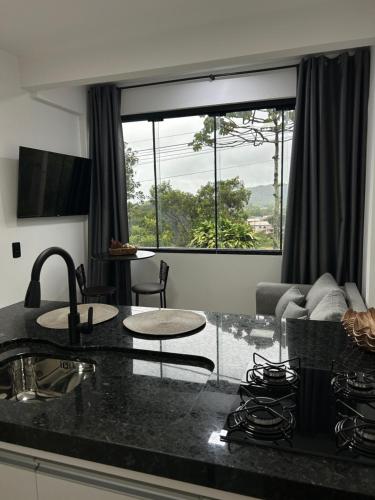 a kitchen with a counter top and a living room at Apto 01 casal praia e vista montanhas in Governador Celso Ramos