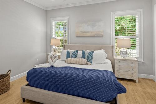 a bedroom with a blue and white bed and two windows at Sweet Bay on 30A in Seagrove Beach