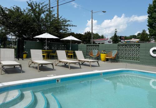 a swimming pool with chairs and a table and umbrella at Colony House Motor Lodge in Roanoke