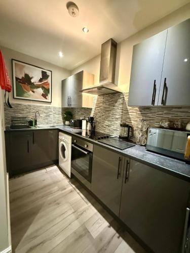 a kitchen with stainless steel appliances and a wooden floor at Cozy Studio Flat in Bradford City Centre in Bradford