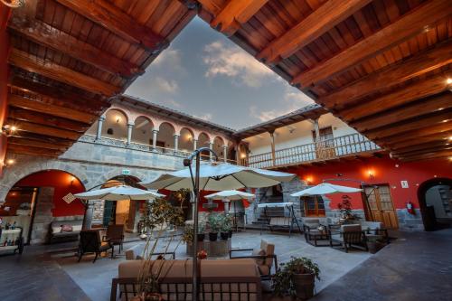a patio with tables and umbrellas in a building at Hotel Hacienda Sonqori Centro Histórico in Cusco