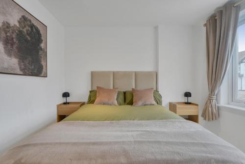 a bedroom with a large bed with two tables at The Friendly Fern Apartment in Bickley