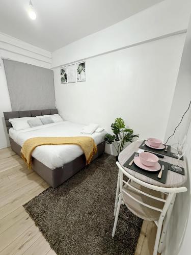 a white bedroom with a bed and a table at Stylish 2-Guest Studio with Netflix, Prime - FREE WIFI & FREE PARKING - Aroluchi Ville in Ecclesfield