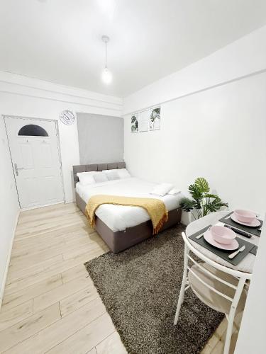 a white bedroom with a bed and a table at Stylish 2-Guest Studio with Netflix, Prime - FREE WIFI & FREE PARKING - Aroluchi Ville in Ecclesfield