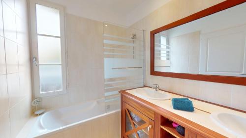 a bathroom with a sink and a tub and a mirror at Villa BlueGreen in Coëx