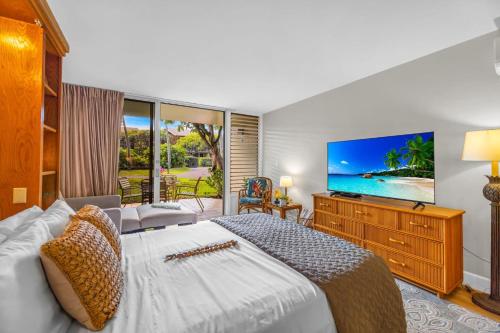 een slaapkamer met een groot bed en een televisie bij Napili Shores D125 in Honokowai