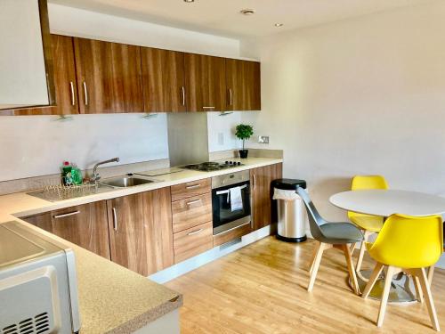 a kitchen with wooden cabinets and a table and yellow chairs at VIPAbodes at Woking Central in Woking
