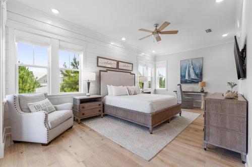a bedroom with a bed and a chair and windows at Sunset Key in Inlet Beach