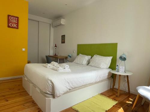 een slaapkamer met een groot wit bed met een groen hoofdeinde bij Fishermans Beach Suites & Rooms Albufeira in Albufeira