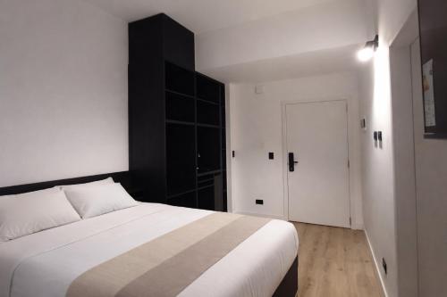 a bedroom with a white bed and a black cabinet at BA Millenium in Buenos Aires