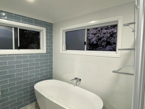 un bagno con vasca e servizi igienici e 2 finestre di Coastal Escape a Kempsey