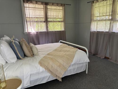 una camera da letto con letto bianco, cuscini e finestre di Coastal Escape a Kempsey