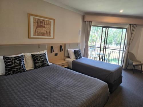 a hotel room with two beds and a balcony at Charbonnier Motor Inn in Singleton