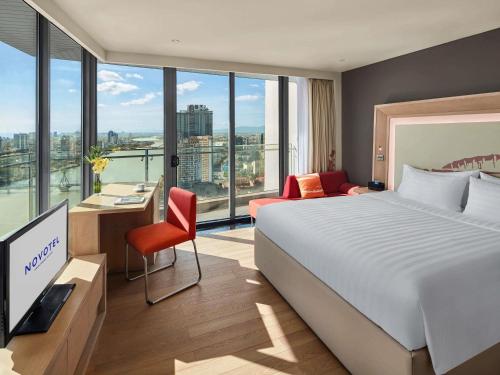 une chambre d'hôtel avec un lit et un bureau avec une télévision dans l'établissement Novotel Danang Premier Han River, à Đà Nẵng