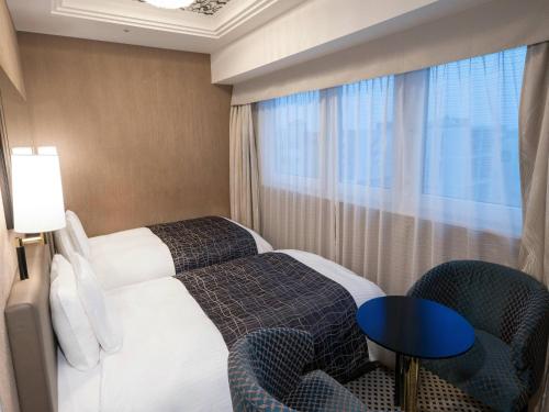 a hotel room with a bed and chairs and a window at APA Hotel Nihombashi Bakurocho Ekimae in Tokyo