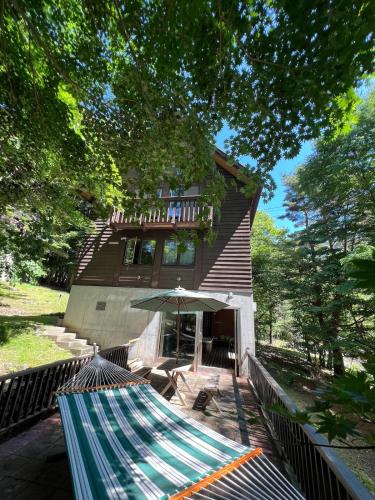 a house with a hammock in front of it at Cabin E Jacuzzi BBQ Hammock Lake Saiko Mt Fuji in Fujikawaguchiko