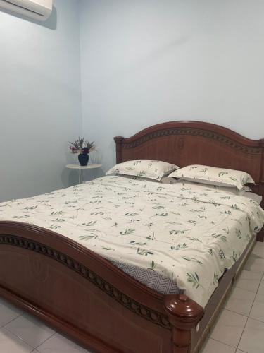 a bed with a wooden frame and white sheets and pillows at Roma Guesthouse Terrace With 3 Bedroom & Airconditioning in Shah Alam