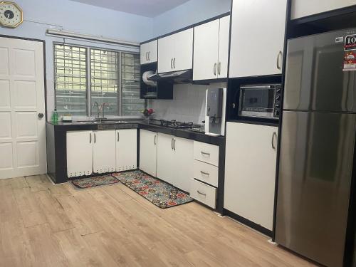 a kitchen with white cabinets and a black refrigerator at Roma Guesthouse Terrace With 3 Bedroom & Airconditioning in Shah Alam