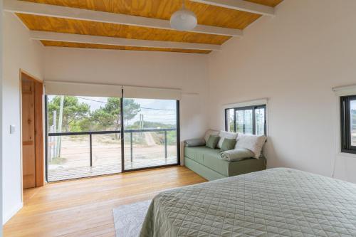 a bedroom with a bed and a couch and a window at Orion in Punta Del Diablo