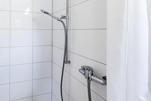 a shower in a bathroom with white tiles at Lea Apartement - Ruhiges Studio in Schaffhausen