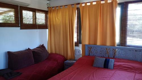 1 Schlafzimmer mit 2 Betten und orangefarbenen Vorhängen in der Unterkunft La Dominga in La Granja