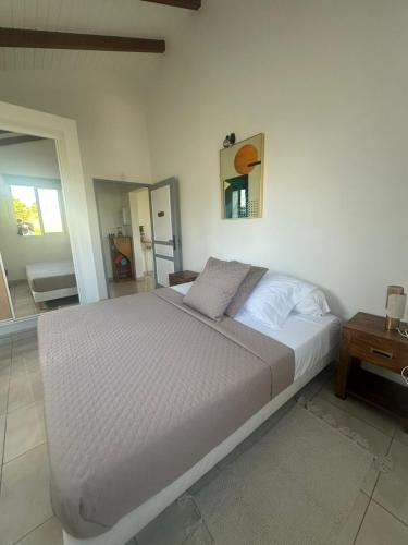 un letto bianco in una camera da letto con tavolo di Les gites de Saint Michel - Purple a Grand-Bourg