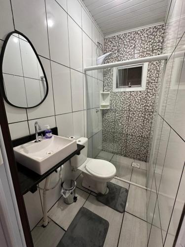 a bathroom with a toilet and a sink and a mirror at Apartamento Amplo em Tramandaí in Tramandaí