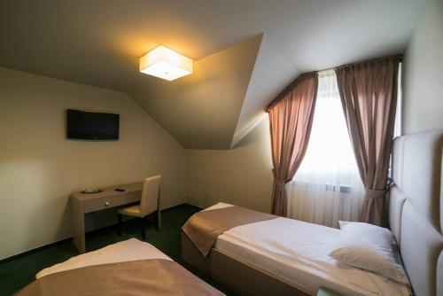 a room with two beds and a desk and a window at Casa Budisteanu in Focşani