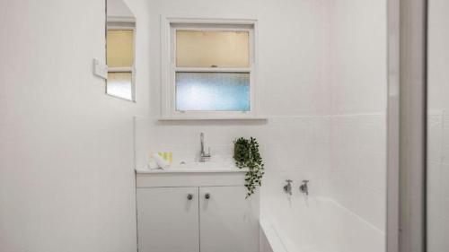 a white bathroom with a sink and a bath tub at Sunnybank House with EV Charger in Cheltenham
