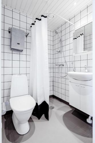 a white bathroom with a toilet and a sink at Hostel Café Koti in Rovaniemi