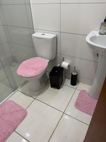 a bathroom with a toilet and a sink and pink mats at Apartamento Sabrina in Curitiba