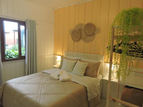 a bedroom with a bed with white sheets and a window at Recanto da Natureza in Imbituba