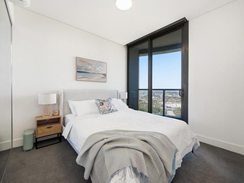 a white bedroom with a bed and a window at The Sky Perch in Sydney
