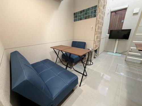 a waiting room with a table and a blue couch at Atami Onsen Apart 103専用温泉付き客室 in Atami