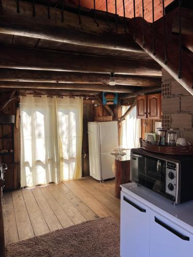 a kitchen with white appliances and a wooden floor at Chalé dos Alves in Morro Azul