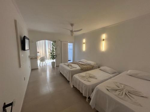 a hotel room with two beds and a hallway at Pousada do Moinho in Cabo Frio