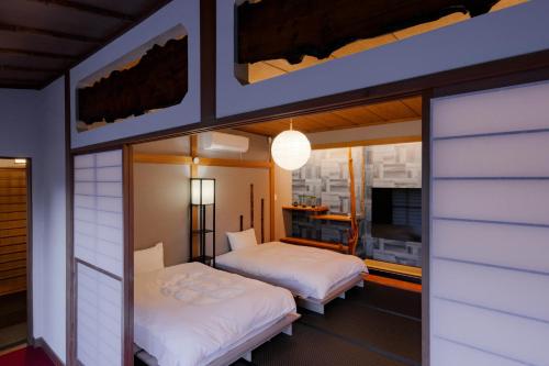 2 aparte bedden in een kamer met een tv bij 樹-Itsuki- "岩風呂付 rockbath" in Hakone