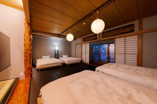 a bedroom with two beds and two pendant lights at 樹-Itsuki- "岩風呂付 rockbath" in Hakone